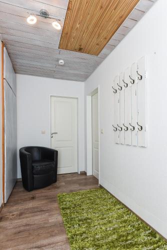 a living room with a black chair and a green rug at Ferienwohnung Haus zum Seehund mit Pool und Frühstücksoption in Bensersiel