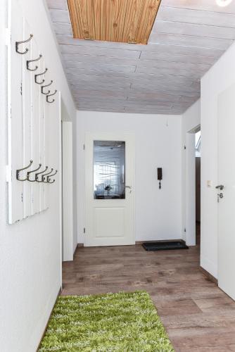 a hallway with white walls and a wooden ceiling at Ferienwohnung Haus zum Seehund mit Pool und Frühstücksoption in Bensersiel