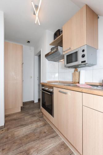 a kitchen with wooden cabinets and a stove at Ferienwohnung Haus zum Seehund mit Pool und Frühstücksoption in Bensersiel