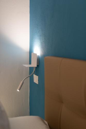 a light on a blue wall next to a bed at L'EMPORIO ROOMS in Manarola