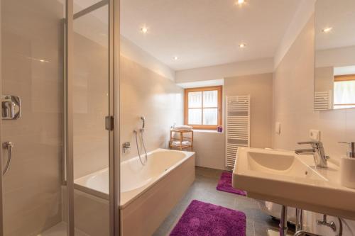 ein Bad mit einer Badewanne, einem Waschbecken und einer Dusche in der Unterkunft Residence Tamperhof in Innichen