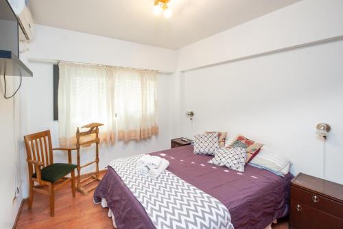 a bedroom with a bed and a chair and a window at Apartamento Micro Centro para 4 con cochera in Bahía Blanca