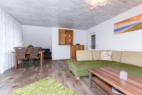 a living room with a green couch and a table at Ferienwohnung Haus zum Seehund mit Pool und Frühstücksoption in Bensersiel