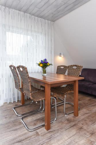 a wooden table with chairs and a vase of flowers on it at Ferienwohnung Haus zum Seehund mit Pool und Frühstücksoption in Bensersiel