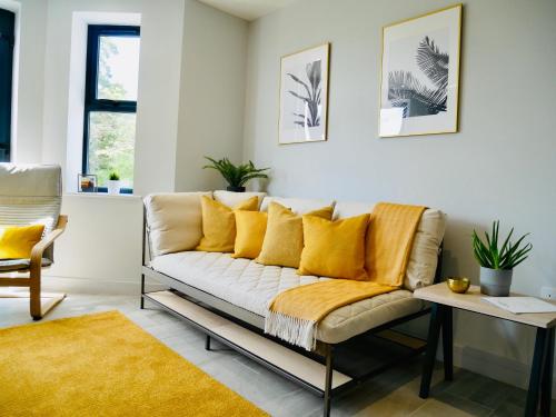 a living room with a couch with yellow pillows at Beautiful AlumPointe Apartment - 400m to the beach in Bournemouth