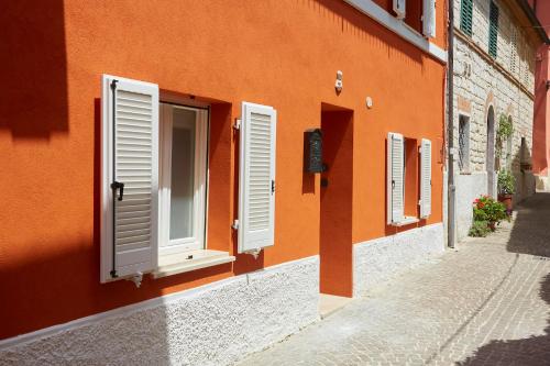an orange building with white shutters on a street at Affittacamere Somnium in Sirolo