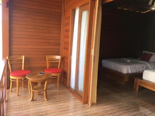 a room with two chairs and a table and a bed at Wahyu Homestay 1 in Nusa Lembongan