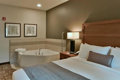 a hotel room with a bed and a bath tub at GrandStay Hotel & Suites in Sisters