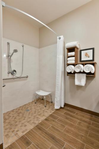 a bathroom with a shower and a bench and towels at GrandStay Hotel & Suites in Sisters