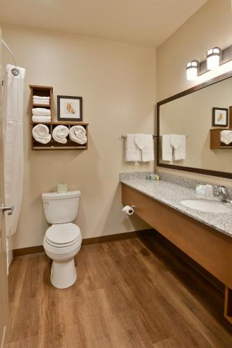 a bathroom with a toilet and a sink and a mirror at GrandStay Hotel & Suites in Sisters