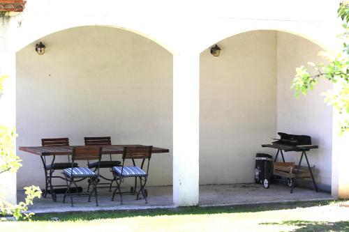 a table and chairs under a white wall with two arches at Le Domaine du Vert bois in Pibrac