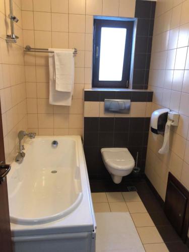 a bathroom with a tub and a toilet and a window at Hotel Brilliant Plaza in Zalău