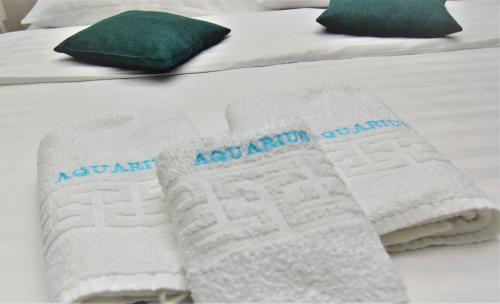 two white towels on a bed with green pillows at Casa AQUARIUS in Caciulata