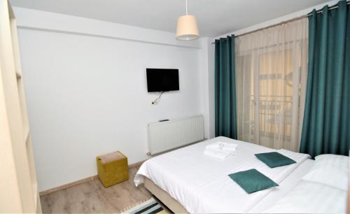 a bedroom with a white bed and a television at Casa AQUARIUS in Caciulata
