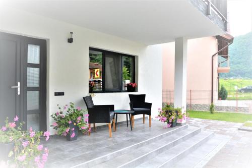 a patio with chairs and a table and flowers at Casa AQUARIUS in Caciulata