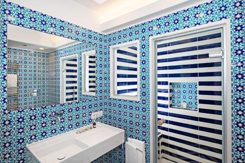 a bathroom with blue tiled walls and a white sink at Imperati Suites by Alcione Residence in Positano