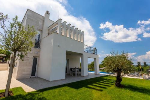a white house with a lawn and a pool at Villa Zarra in Klimno