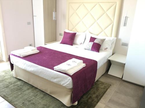 Un dormitorio con una cama grande con sábanas y almohadas púrpuras. en Alludo Aparthotel b&b en Agrigento