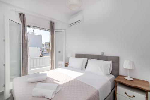 a bedroom with a large white bed with a window at Lux 'n Comfort Apartments in Tinos