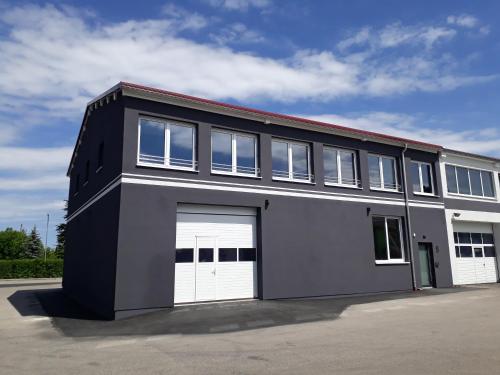 a black and white building with two white garage doors at Das Fischer Boardinghouse BW in Bad Wörishofen