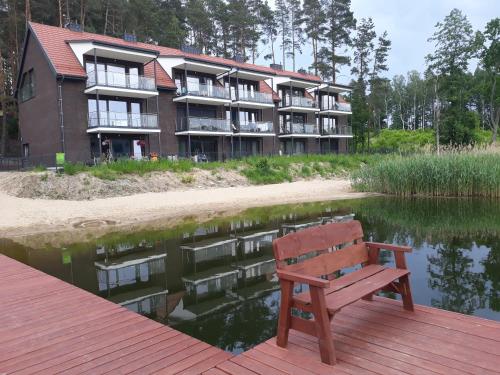 a wooden bench sitting on a dock in front of a building at Mazurskie Klimaty Tatarak in Olsztyn