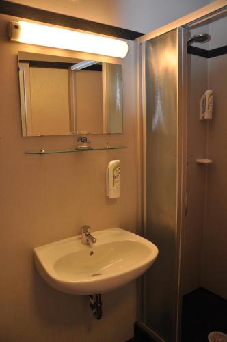 a bathroom with a sink and a mirror and a shower at MOTEL ARBOTEL 24h self check-in in Friesach