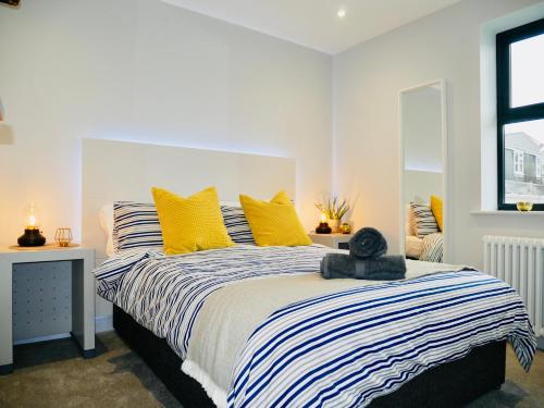 a bedroom with a large bed with yellow pillows at Beautiful Brand New Apartment near the BEACH in Bournemouth