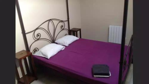 una camera con letto viola con struttura nera di Pavillon bon enfant a Saint-Priest
