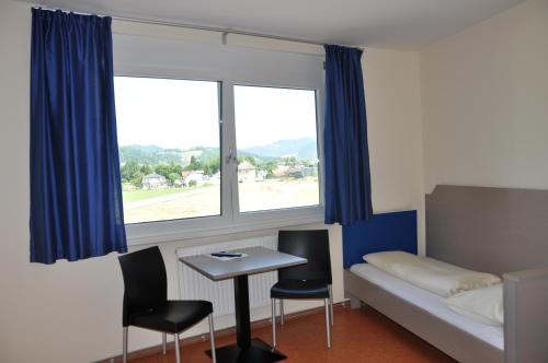 a room with a bed and a table and two chairs at MOTEL ARBOTEL 24h self check-in in Friesach