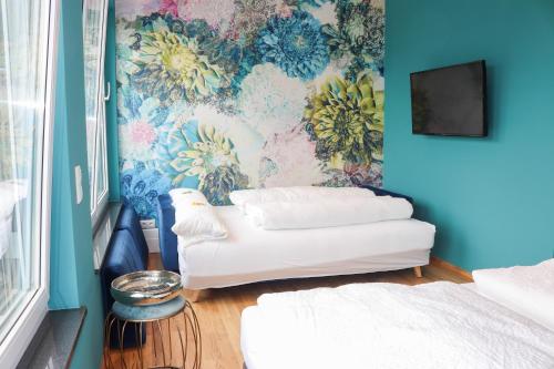 a room with a couch and a floral wall at Das Fischer Boardinghouse BW in Bad Wörishofen
