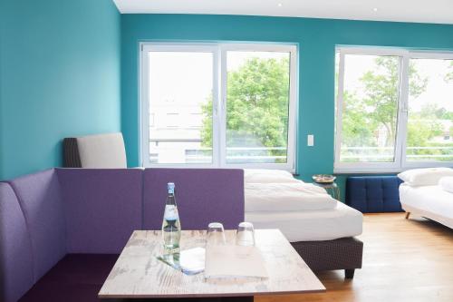 a room with a couch and a table with a bottle of wine at Das Fischer Boardinghouse BW in Bad Wörishofen