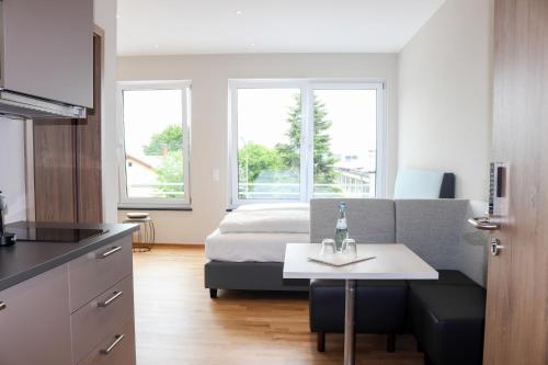 a bedroom with a bed and a table with a bottle on it at Das Fischer Boardinghouse BW in Bad Wörishofen