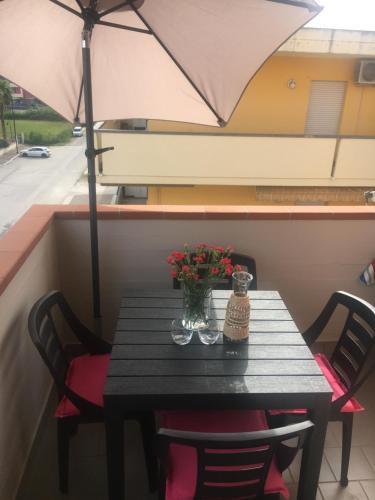 une table avec un vase de fleurs et un parasol dans l'établissement apartmentsIT via Verona 16, à Alba Adriatica