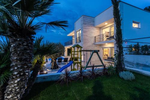 a house with a palm tree in front of it at Villa Zarra in Klimno