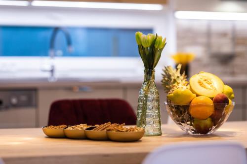 a table with a bowl of fruit and a vase of flowers at Villa Zarra in Klimno