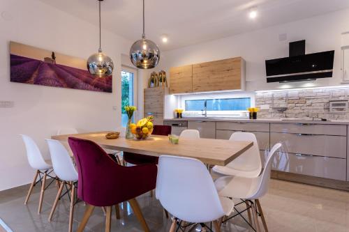 a kitchen with a wooden table and white chairs at Villa Zarra in Klimno