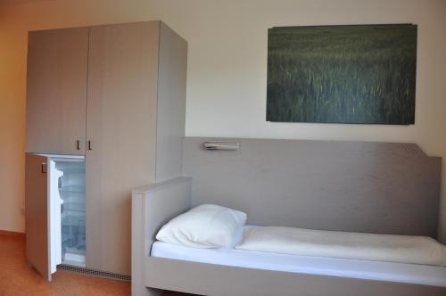 a small bedroom with a bed and a cabinet at MOTEL ARBOTEL 24h self check-in in Friesach