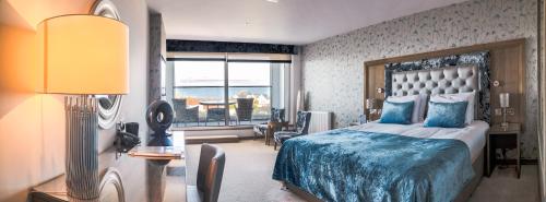 a bedroom with a bed with a blue blanket and a window at Seamill House Hotel in Seamill
