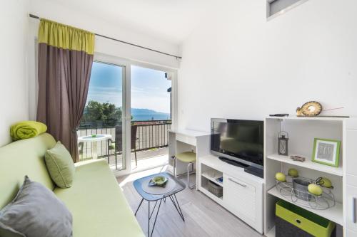 a living room with a couch and a tv and a balcony at Apartments Stinice in Gradac