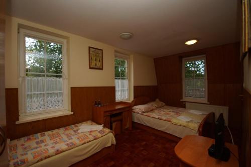 Zimmer mit 2 Betten, einem Tisch und 2 Fenstern in der Unterkunft Prohibicja Peter's Pub in Mikołajki