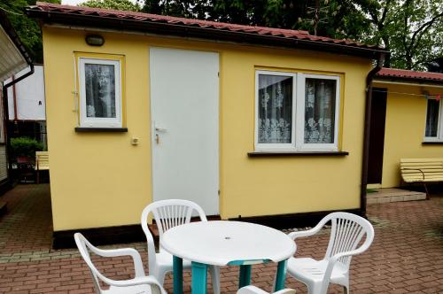 a table and chairs in front of a yellow house at Domki letniskowe U GOSI in Trzęsacz