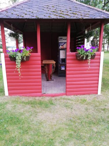 a red building with two flower boxes and a table at Kempings Mežmalas in Usma