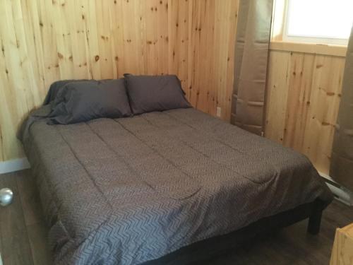 a bed in a room with a wooden wall at Chalet Les Parulines in Tadoussac