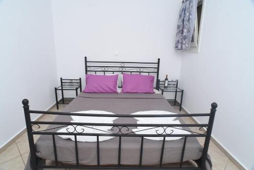 a bedroom with a black bed with pink pillows at Little Yard Studios & Apartments #3 in Naxos Chora