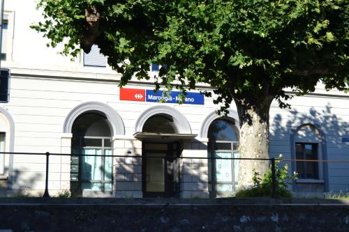 a white building with a tree in front of it at Hotel della Stazione in Maroggia