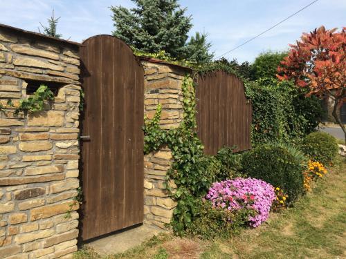 a wooden gate in a stone wall with flowers at Clara Valis - Village House in Doľany