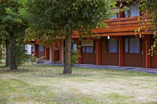 a red building with trees in front of it at Campanile Lille Sud - Douai Cuincy in Cuincy