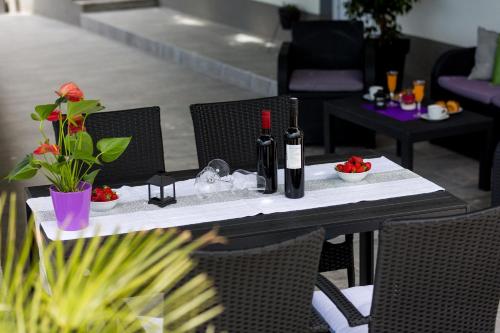 a table with two bottles of wine and flowers on it at Apartments Lidija - sea view apartment with exclusive right of using hot tub or split level apartment with exclusive right of using pool in Podstrana