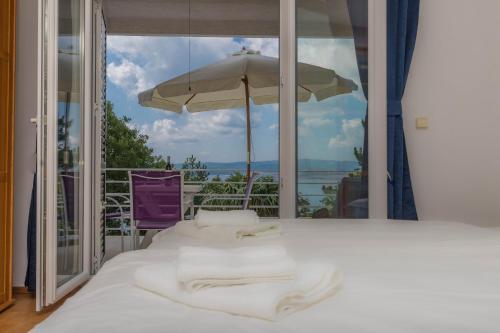 ein Bett mit weißer Bettwäsche und einem Sonnenschirm auf dem Balkon in der Unterkunft Apartments Martina in Jadranovo