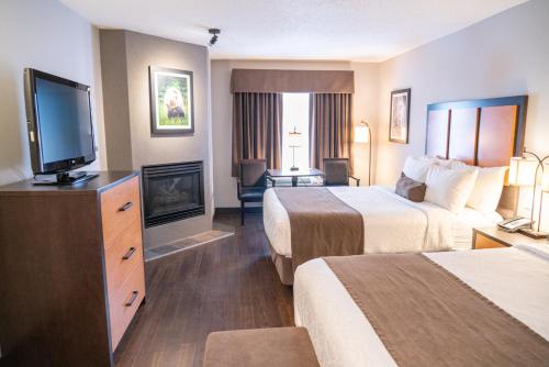 a hotel room with two beds and a flat screen tv at Pocaterra Inn & Waterslide in Canmore